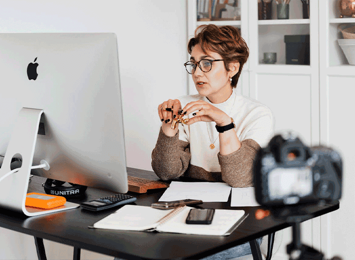 Uma mulher sentada em uma mesa em frente a um computador
