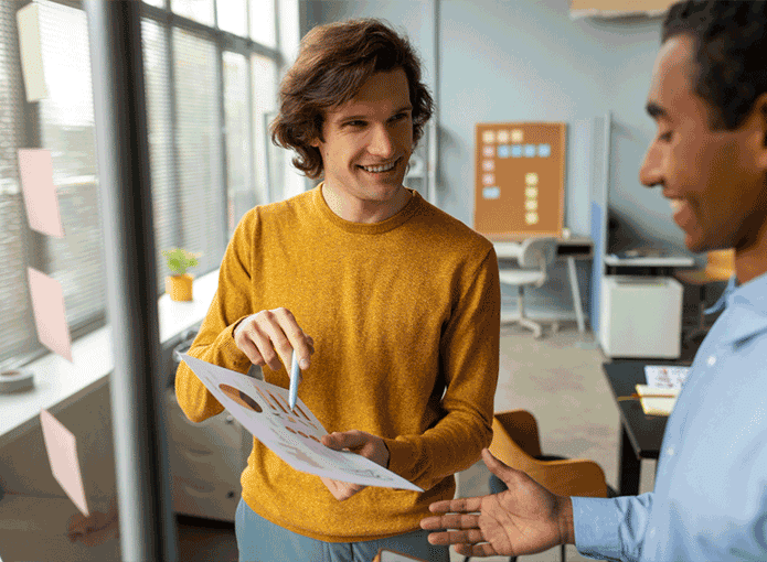 Dois homens sorrindo e olhando para um papel com dados