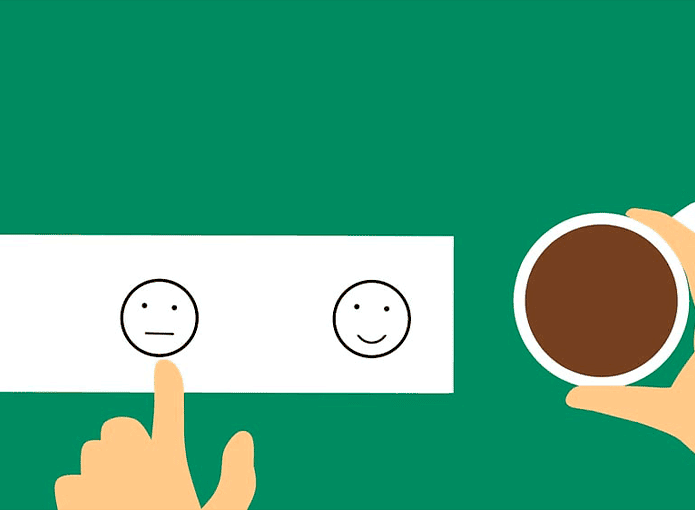 Desenho com mão esquerda apontando para um emoji enquanto a direita segura um café