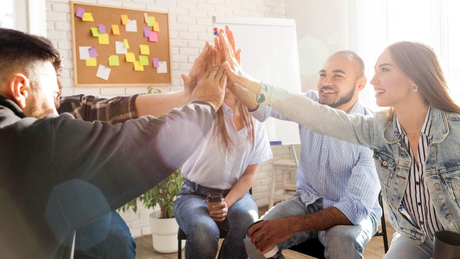 Grupo de pessoas comemorando com high five em ambiente corporativo