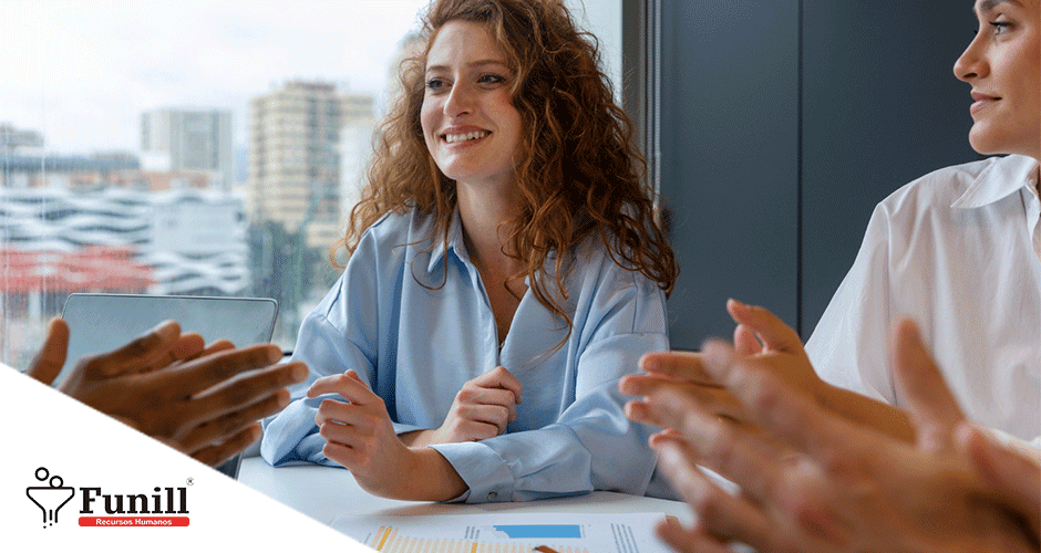 Mulher sorridente recebendo reconhecimento da equipe durante reunião no escritório